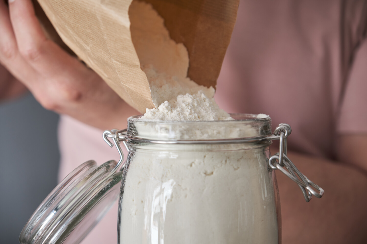 man filling up a jar with wheat flour 